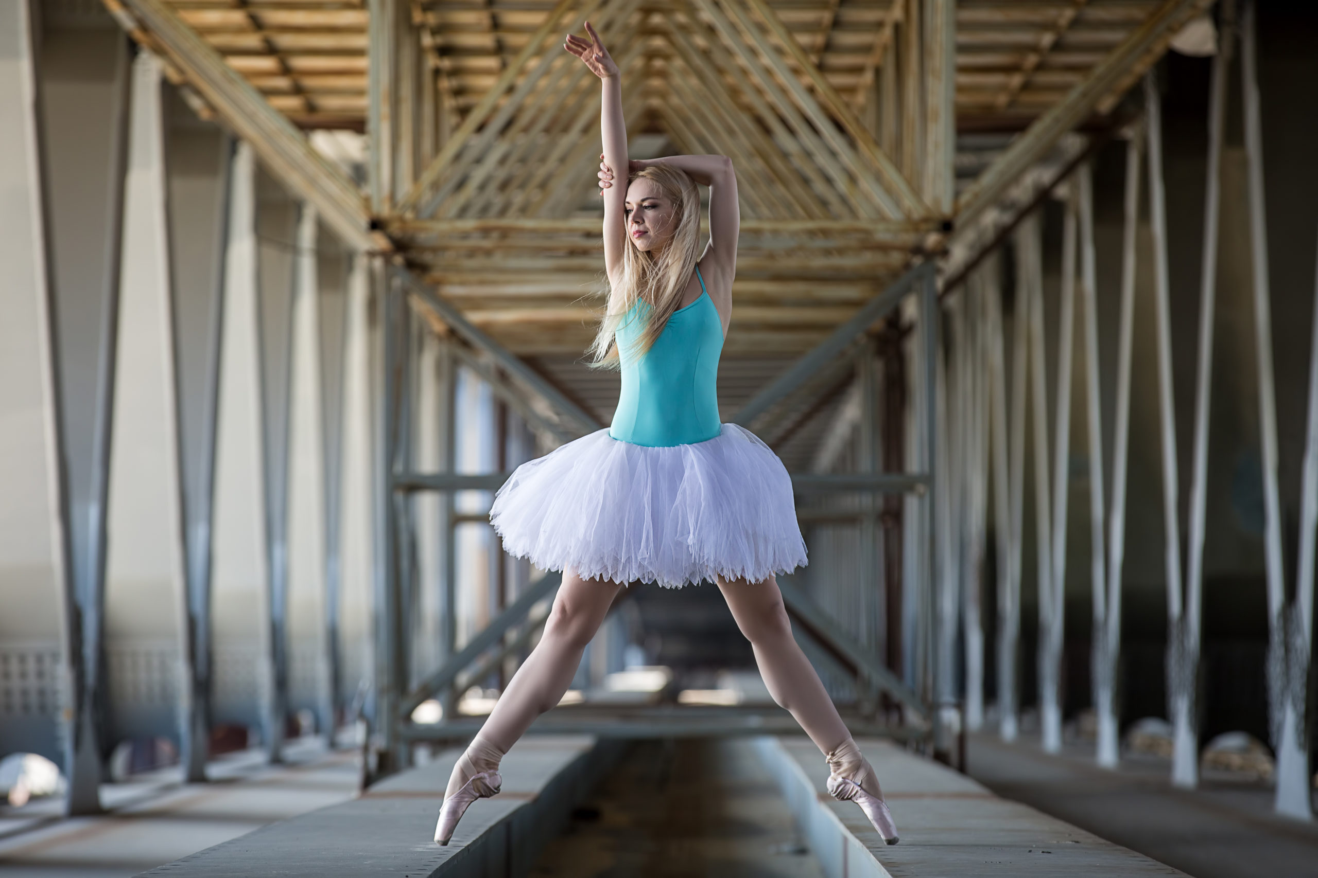 Graceful ballerina in white tutu in the industrial background of the bridge.